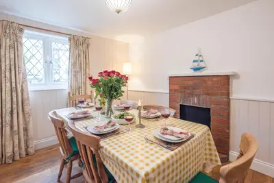 a dining room with a table and a fireplace at Ann Page Cottage, Aldeburgh in Aldeburgh