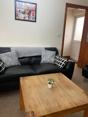 a living room with a black couch and a wooden table at Two Bedroom Bungalow No2 - Secure Gated Parking in Basildon