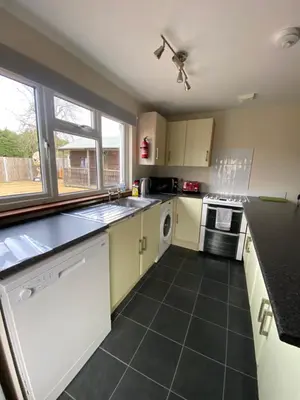 a kitchen with white cabinets and a black tile floor at Two Bedroom Bungalow No2 - Secure Gated Parking in Basildon