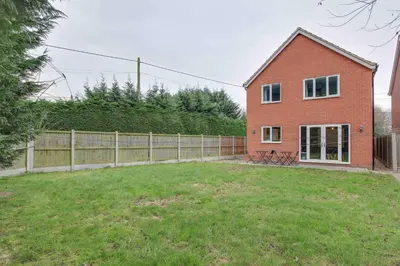 a red brick house with a fence and a yard at Blackwater Villa Witham in Witham