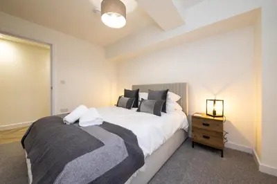 a bedroom with a large bed and a night stand at Flat in Royston Town Centre in Royston