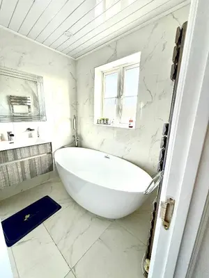 a white bathroom with a large tub and a window at Rose home in Haverhill