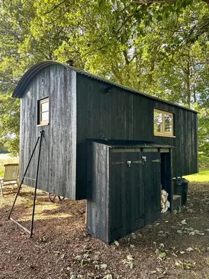 a black shed with a door and a window at Secret Paddock Shepherds Hut in Hollesley