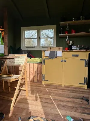 a kitchen with a counter and a table in a room at Secret Paddock Shepherds Hut in Hollesley