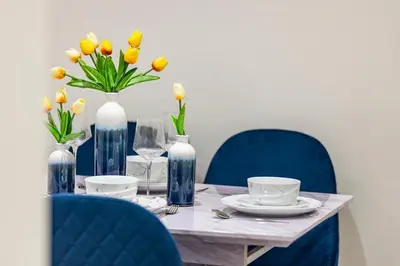 a table with blue chairs and vases with yellow flowers at Modern 2 Bed Gem Southend on Sea Free parking in Southend-on-Sea