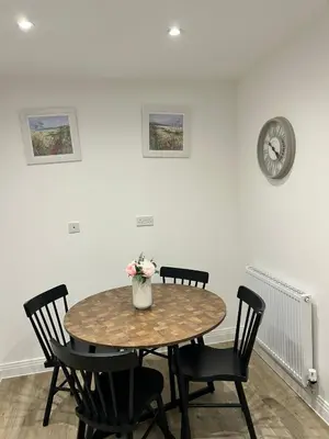 a table with chairs and a clock on a wall at The Belles' Place near Colchester in Earls Colne
