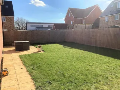 a backyard with a fence and a yard withgrass at Detached Place to stay in Essex in Witham