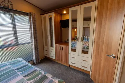 a bedroom with a bed and a dresser and a tv at Caravan Hire Mersea Island - EOEPS in East Mersea