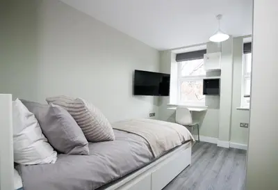 a bedroom with a bed with a tv on the wall at Ryegate House Colchester in Colchester