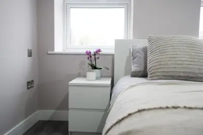 a white bedroom with a bed and a window at Ryegate House Colchester in Colchester