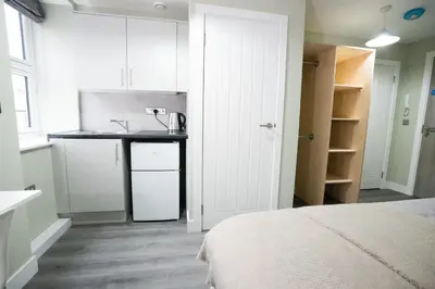 a small kitchen with a sink and a bed in a room at Ryegate House Colchester in Colchester