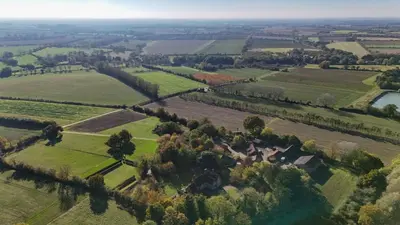 an aerial view of a field with trees and a river at 'Bramley' Hut on private farm in Charsfield