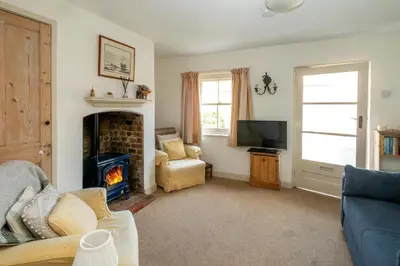 a living room with a fireplace and a tv at Ginnys Cottage by Aldeburgh Coastal Cottages in Aldeburgh