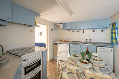 a kitchen with blue cabinets and a table with plates on it at Ginnys Cottage by Aldeburgh Coastal Cottages in Aldeburgh