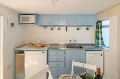 a small kitchen with blue cabinets and a sink at Ginnys Cottage by Aldeburgh Coastal Cottages in Aldeburgh