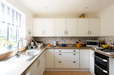 a kitchen with white cabinets and a sink at 2 Admirals Walk by Aldeburgh Coastal Cottages in Thorpeness