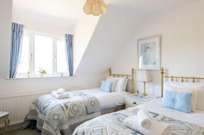 two beds in a room with blue curtains at 2 Admirals Walk by Aldeburgh Coastal Cottages in Thorpeness