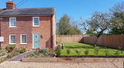 a brick house with a garden and a fence at Fully Refurbished 3 bed Victorian Cottage in Tolleshunt D'Arcy in Tolleshunt DʼArcy