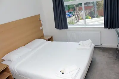 a bedroom with a bed with two white shoes on it at Gidea Park Hotel in Romford