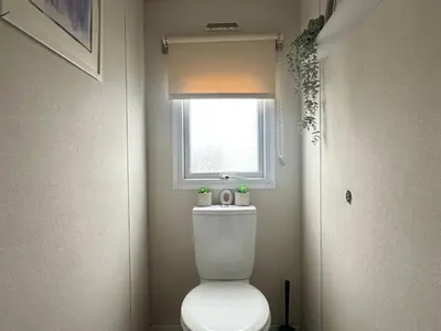 a bathroom with a toilet and a window at Harwich - Caravan - Sleeps 10 - Garden - Pool in Harwich