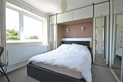 a bedroom with a large bed and a mirror at Modern home in historic market town near airport in Saffron Walden