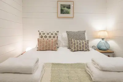 a white bedroom with a white bed with pillows at Sea Holly Cottage, Aldeburgh in Aldeburgh