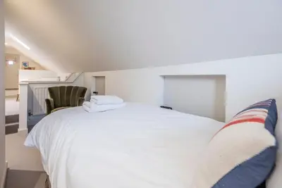 a bedroom with a white bed and a chair at Sea Holly Cottage, Aldeburgh in Aldeburgh