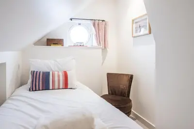 a bedroom with a bed and a chair at Sea Holly Cottage, Aldeburgh in Aldeburgh