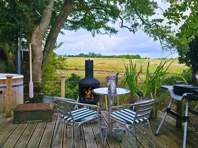 a patio with a table and chairs and a stove at The Pheasant in Great Ellingham