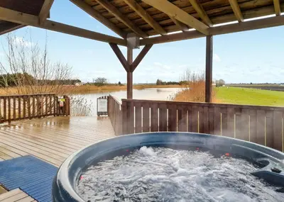 a hot tub on a deck next to a body of water at Fenview Lakes in Ely