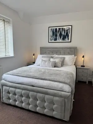 a white bedroom with a large bed with white sheets at Park Villa, Stevenage in Shephall