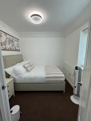 a white bedroom with a bed and a window at Park Villa, Stevenage in Shephall