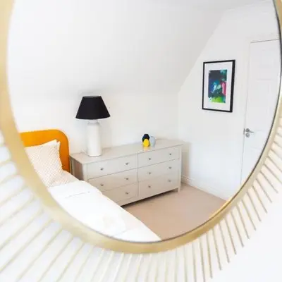 a mirror reflecting a bedroom with a bed and a dresser at 5 Bed Family Home- Free Parking in Woodham Ferrers Station