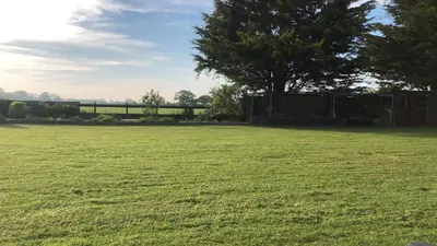 a large green field with a fence and trees at Country View place in Weeley