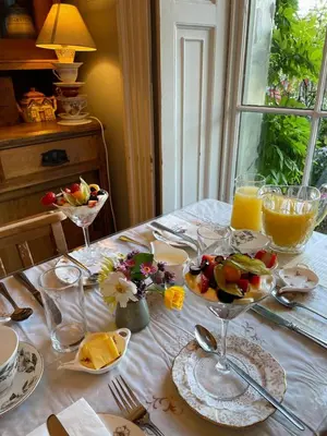 a table with a bowl of fruit and glasses of orange juice at Peacocks Tearoom and Fine B&B in Ely