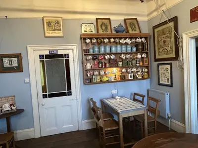 a dining room with a table and a shelf at Peacocks Tearoom and Fine B&B in Ely