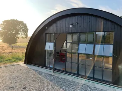 a large metal building with a large glass door at Converted Nissen Barn on beautiful farm in Braintree