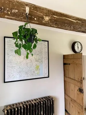 a map and a clock on a wall with a plant at Farmhouse in Suffolk with wild swimming & hot tub in Saint Margaret