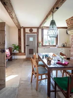 a kitchen and dining room with a wooden table and chairs at Farmhouse in Suffolk with wild swimming & hot tub in Saint Margaret