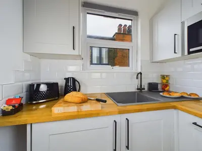 a kitchen with white cabinets and a counter top with a sink at Westcliff apartment with free parking in Southend-on-Sea