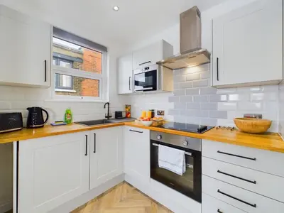 a kitchen with white cabinets and wooden counter tops at Westcliff apartment with free parking in Southend-on-Sea