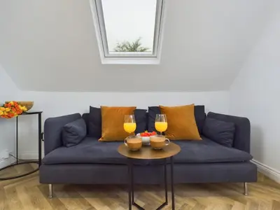 a blue couch with two glasses of wine on a table at Westcliff apartment with free parking in Southend-on-Sea