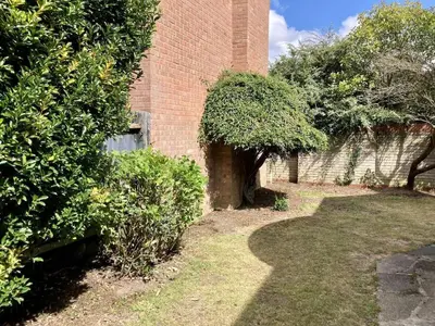 a brick building with bushes and trees next to it at Brackens House Brentwood in Little Warley