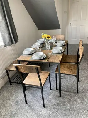 a wooden table with plates and glasses and flowers on it at Brackens House Brentwood in Little Warley
