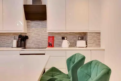 a kitchen with white cabinets and a green at Foxglove House & Hot Tub Stansted Airport in London Stansted Airport