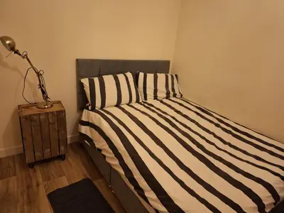 a bed with a black and white striped comforter and a lamp at Happy place in Milton