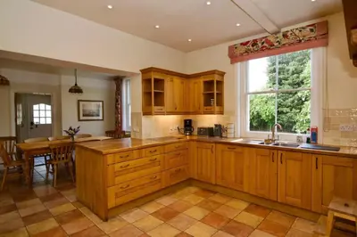 a large kitchen with wooden cabinets and a table at Beautiful country home and garden in Kirby Cross