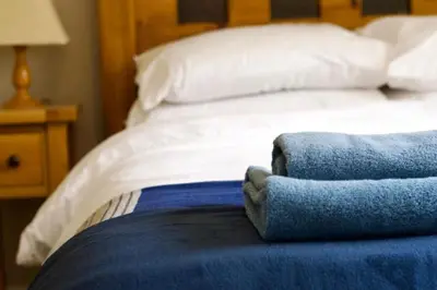 a bed with white sheets and blue towels on it at Beautiful country home and garden in Kirby Cross
