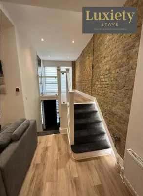a living room with a staircase and a brick wall at Sleek & Stunning 2BR APT By Luxiety Stays Short Lets & Serviced Accommodation Southend on sea With Free WiFi, Smart TV, Netflix in Southend-on-Sea