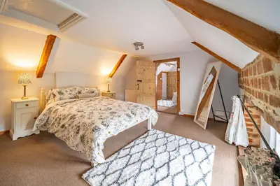 a bedroom with a bed and a brick wall at Swift Host - 2 Bedrooms - Period Cottage - Garden - Village Location - Dog Friendly in Hockham